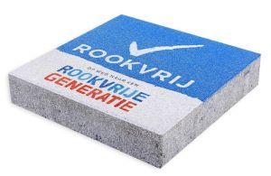 De rookvrij-stoeptegel is blauw met het rookvrij logo. Onderaan staat 'op weg naar een rookvrije generatie'.